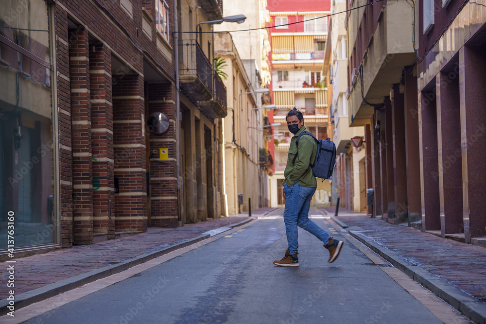 Man crossing the street with backpack on his back