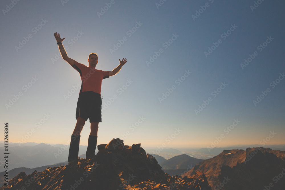 Low angle view of man standing on mountain with arms raised against clear sky during sunset Low angle view of man standing on mountain with arms raised against clear sky during sunset