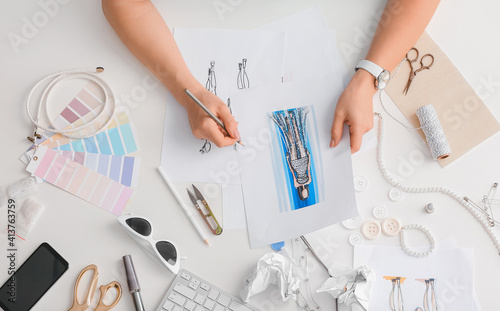 Female fashion designer working with sketches in studio, closeup