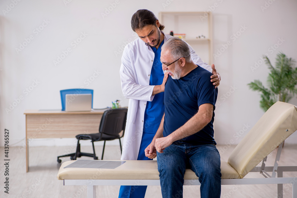 Old male patient visiting young male doctor chiropractor