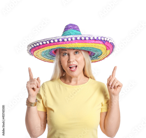 Mature Mexican woman in sombrero hat pointing at something on white background