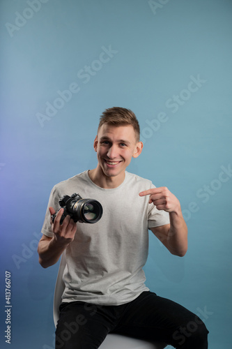 Handsome young photographer using camera on blue background