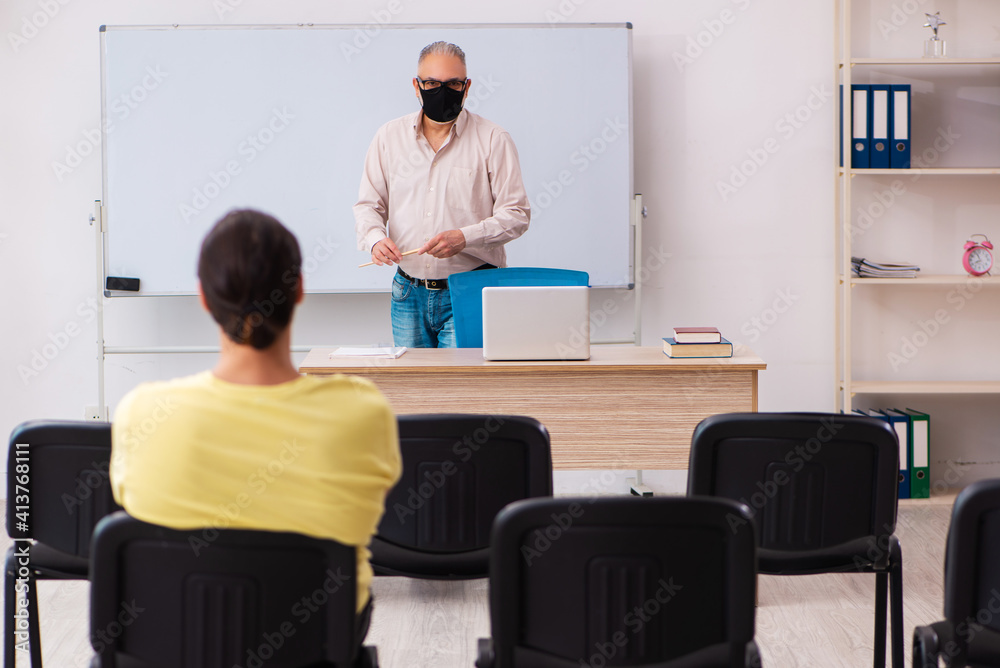 Young male student and experienced teacher in pandemic concept Young male student and experienced teacher in pandemic concept