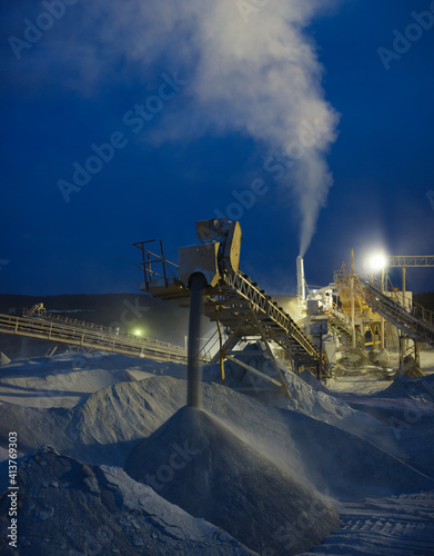 Details of stone crushing equipment at a mining enterprise in the dark time, long exposure, close-up panorama. Quarry mining machinery.