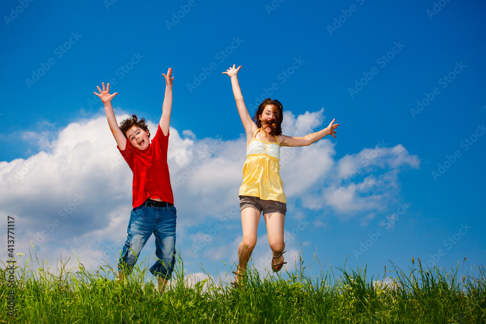Girl and boy running, jumping against blue sky
Girl and boy running, jumping against blue sky