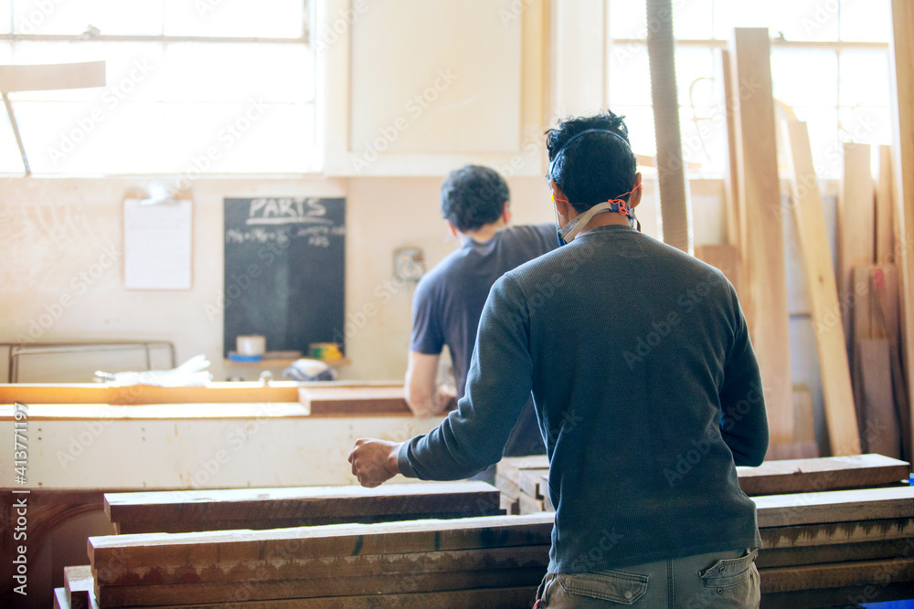 Rear view of male carpenters working in workshop Rear view of male carpenters working in workshop