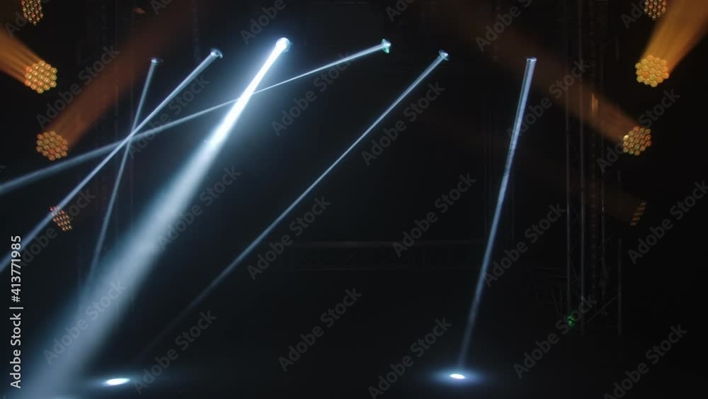 Colorful stage lights. Gold spotlights and white laser holograms spins, turns and emits light bright beams. Lighting equipment and light effects for design, concert hall and stage lighting during show
