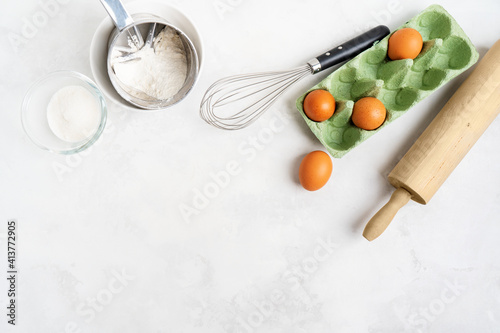 Kitchen background for mockup with eggs, rolling pin, bowls for cooking and baking utensils on the table on white background. Blank space for a text, home kitchen decor concept. Wide banner.