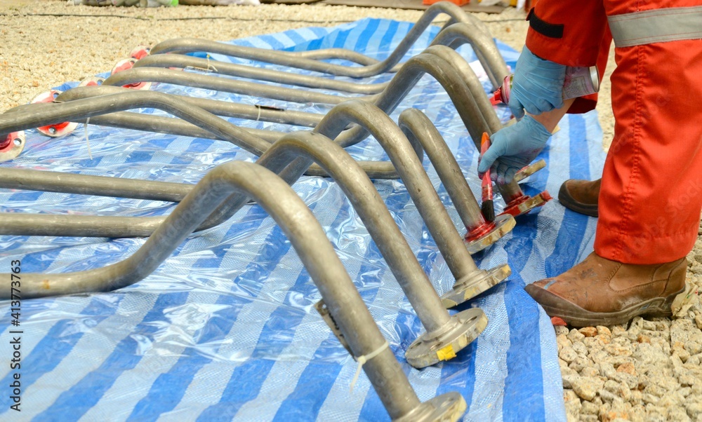 Worker are apply the penetrate to the welding of stainless steel pipe with a brush for finding the defect. This is first step of penetration testing (PT). Worker are apply the penetrate to the welding of stainless steel pipe with a brush for finding the defect. This is first step of penetration testing (PT).