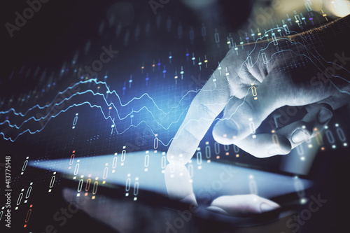 Double exposure of man's hands holding and using a digital device and forex graph drawing. Financial market concept.