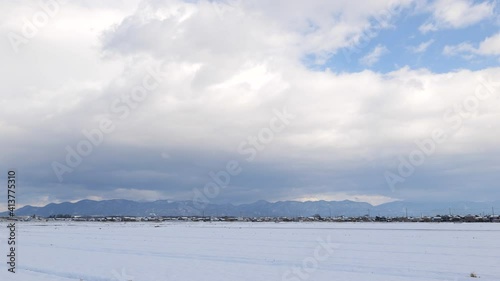 Shiga Prefecture in winter, huge clouds and the Suzuka Mountains seen beyond the snowfield. photo