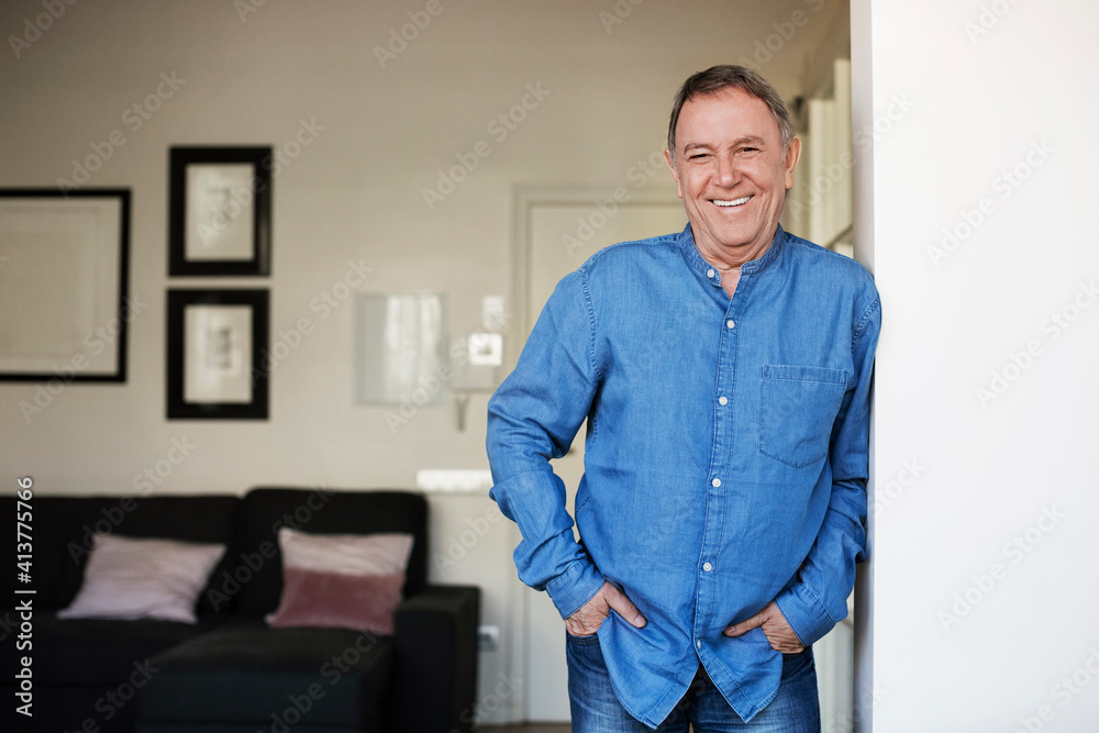Portrait of happy senior man standing with hands in pockets at home Portrait of happy senior man standing with hands in pockets at home