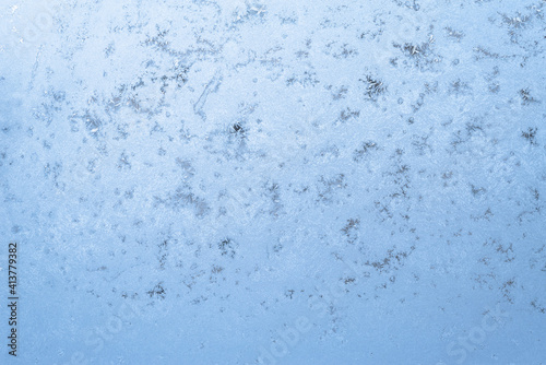 frozen glass in the cold, icy blue pattern in winter on the window. the texture of the ice and snowflakes
