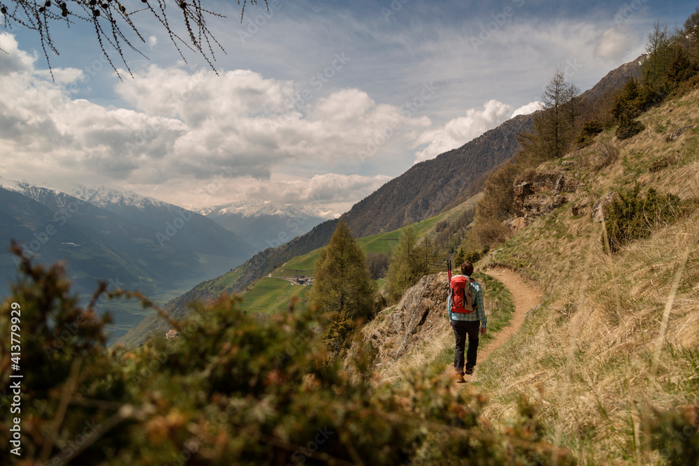 Rear view of female hiker walking on mountain against cloudy sky Rear view of female hiker walking on mountain against cloudy sky