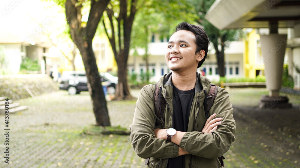 Portrait of smiling Asian man with backpack standing and staring at the camera Portrait of smiling Asian man with backpack standing and staring at the camera