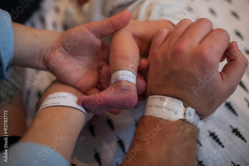 Cropped image of parents and newborn baby with hospital identification bracelets