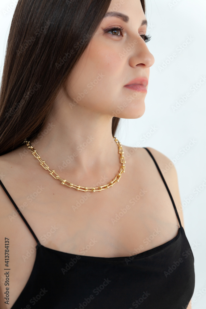 Beautiful model brunette in modern gold metal necklace chain