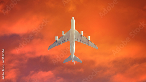 Ultra wide panoramic ground zoom photo of passenger airplane flying above at sunset with beautiful orange sky and clouds