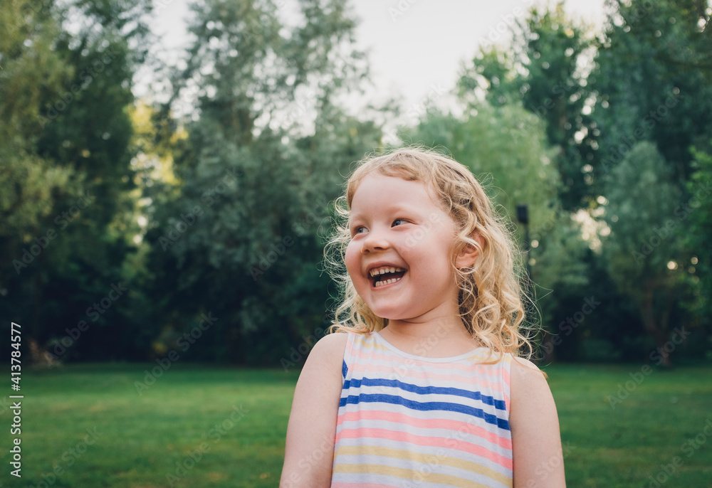 Cheerful girl looking away while standing at park Cheerful girl looking away while standing at park