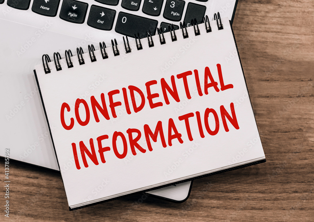 CONFIDENTIAL INFORMATION - inscription on notepad on laptop keyboard. CONFIDENTIAL INFORMATION - inscription on notepad on laptop keyboard.
