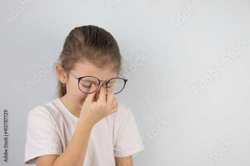 little girl wipes tired eyes from glasses, cute child feeling discomfort and fatigue,tired after long wearing spectacles,eyesight problem,isolated on white background,eye fatigue