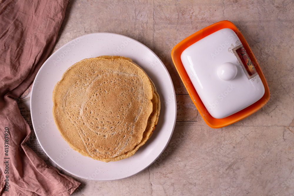 Oatmeal pancakes with on a round plate and butter dish on a beige background. Oatmeal pancakes with on a round plate and butter dish on a beige background.
