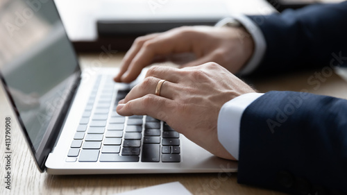 Crop close up of businessman use modern computer texting typing online on gadget. Male employee consult business client or customer distant on laptop  write email on device. Technology concept.