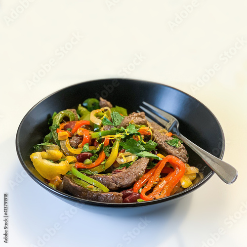 Mexican beef fajitos in a black plate on a white background