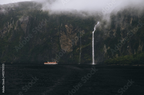 Tourist ferry approaching waterfall at Milford Sound during foggy day. photo