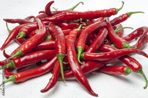 Red and ripe hot chillies arranged on a white table. Such peppers are perfect for spicy Asian or Mexican dishes  but not only.