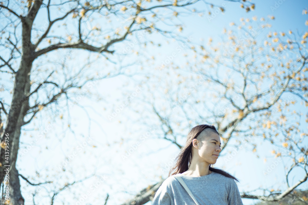 Asian girl with blue sky and large yellow flower tree Asian girl with blue sky and large yellow flower tree
