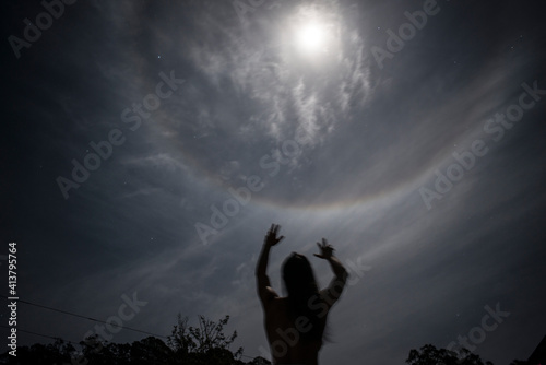 Finger reaches for full moon at night photo