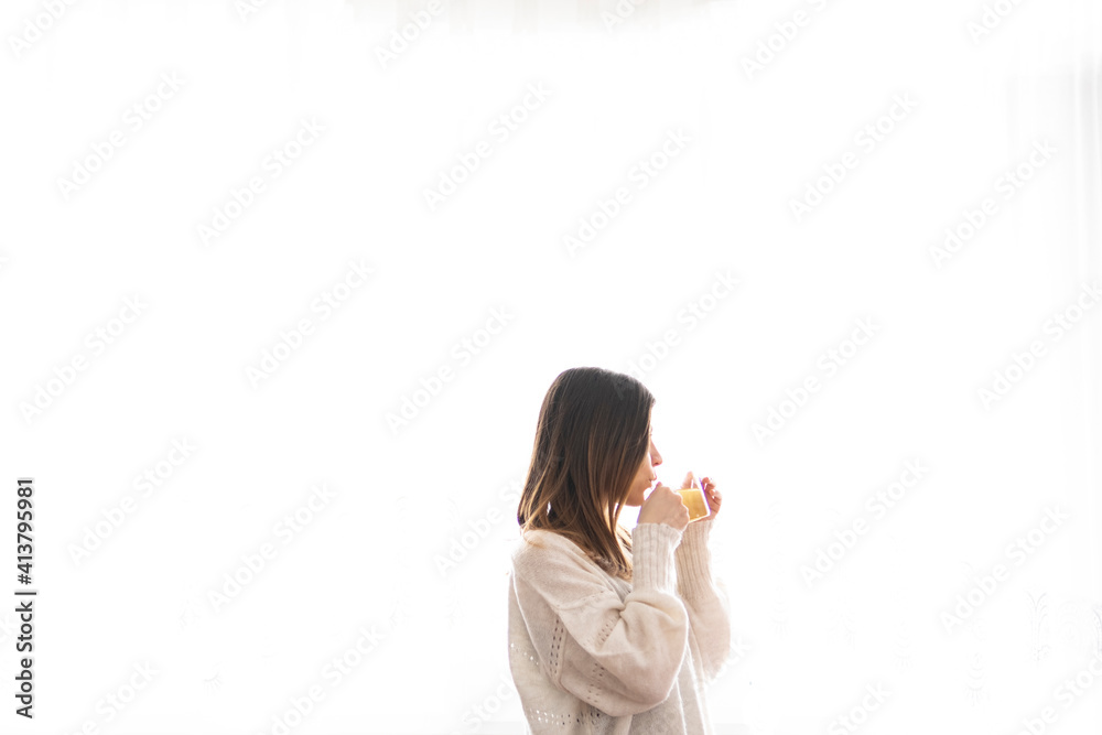 Young woman drinking morning tea in her home.Woman is look around and drinking relax tea by the window. Young woman drinking morning tea in her home.Woman is look around and drinking relax tea by the window.