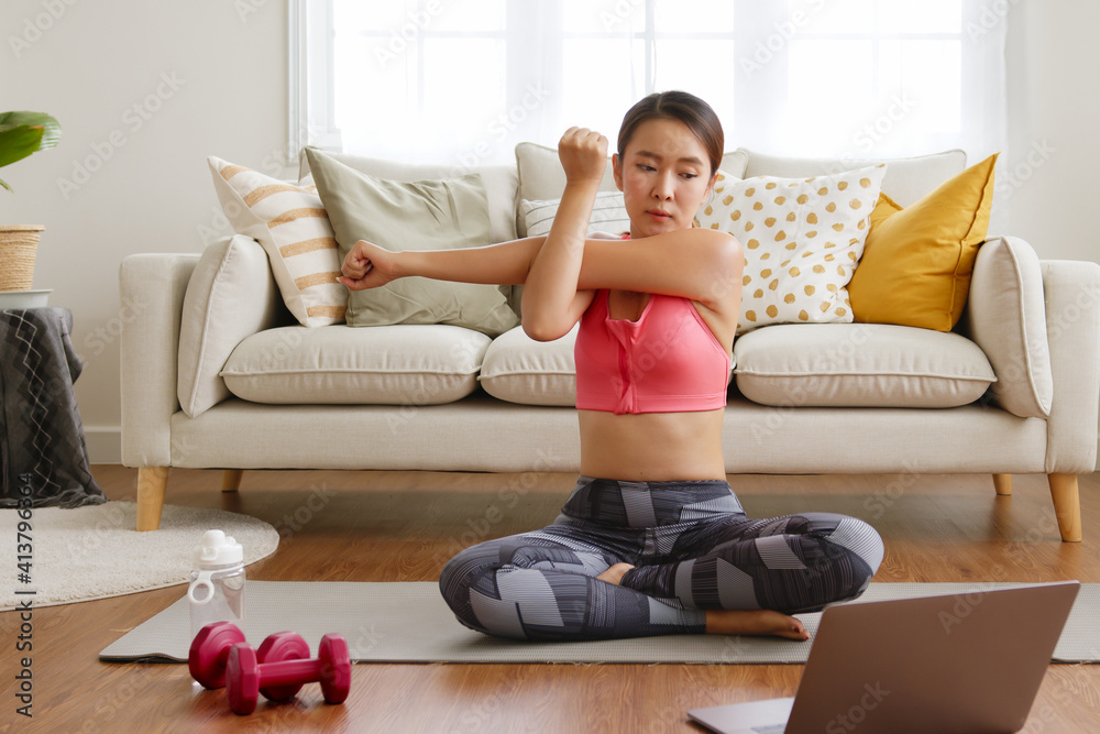 Sporty woman doing yoga and exercise at home, workout training online with coach on laptop in living room Sporty woman doing yoga and exercise at home, workout training online with coach on laptop in living room