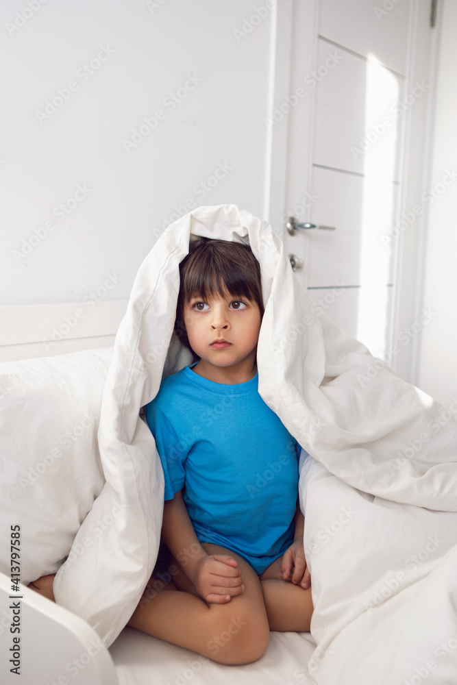 child boy lies in a white children's bed with a blanket in a room with toys rabbits child boy lies in a white children's bed with a blanket in a room with toys rabbits