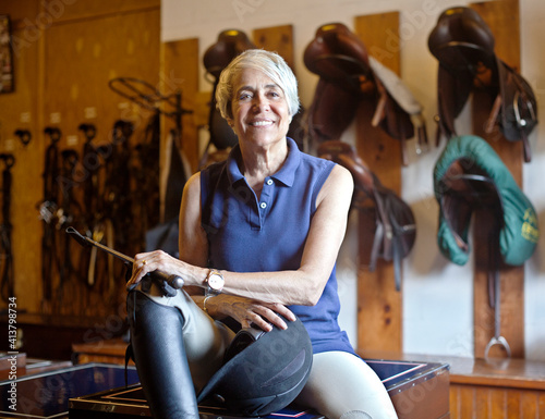 Portrait of smiling jockey sitting on table in stable