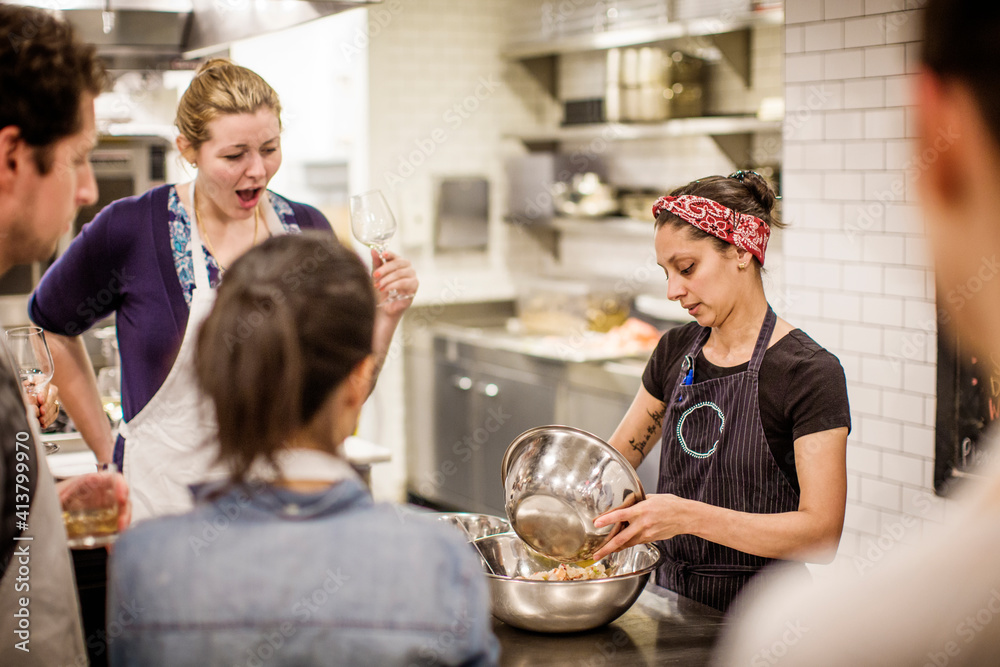 Female chef teaching while standing at table in commercial kitchen