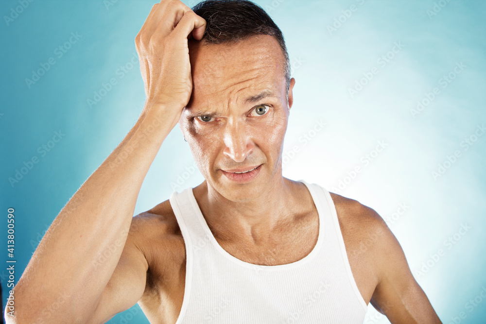 Portrait of man holding head in hand against blue background
