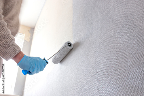 Fototapeta Naklejka Na Ścianę i Meble -  Man painting wall using a paint roller. Do it yourself concept