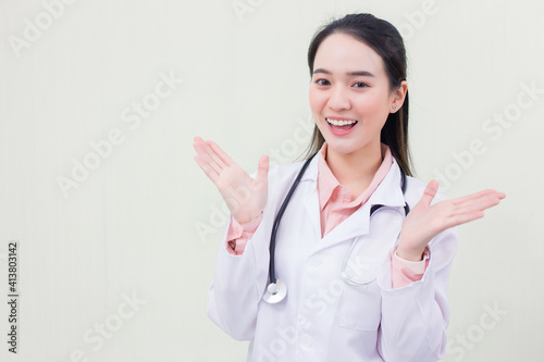 Beautiful young Asian woman doctor smiling cheerfully showing gestures in a medical gown