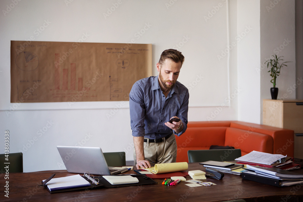 Man using smart phone while working in office Man using smart phone while working in office