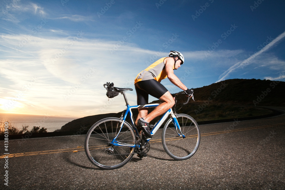 Side view of cyclist riding bicycle on road against sky Side view of cyclist riding bicycle on road against sky