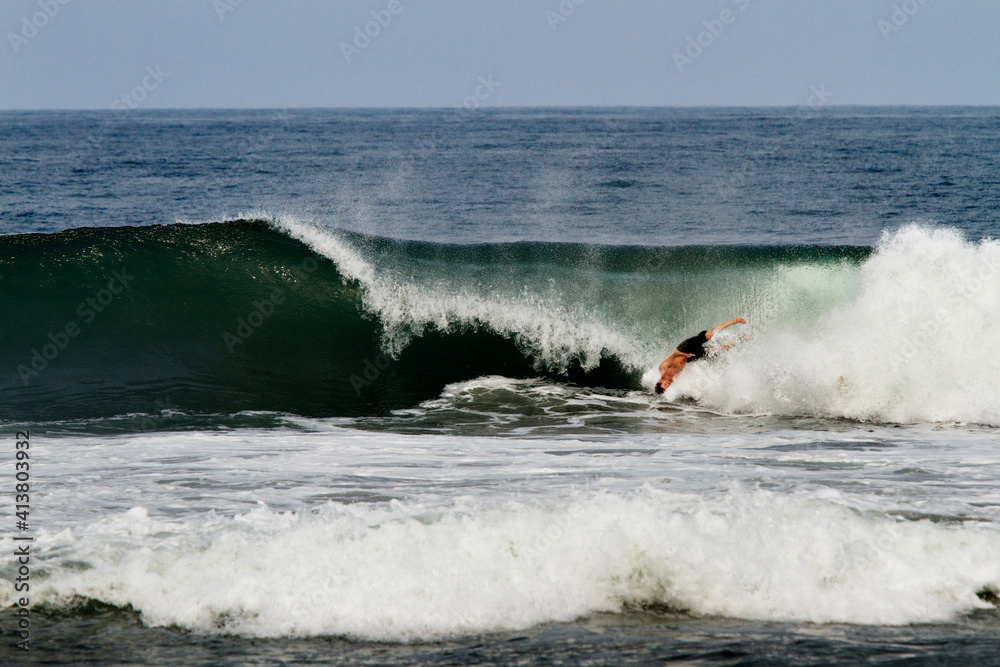 Man swimming in huge sea waves against sky Man swimming in huge sea waves against sky