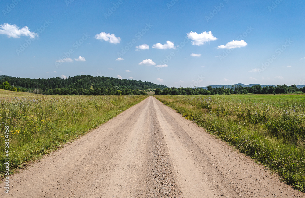 Gravel road in field, rural landscape at summer