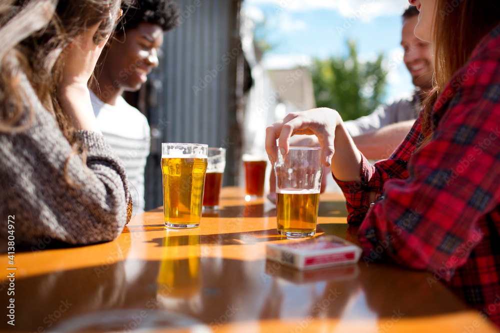 Friends having beer at table in brewery on sunny day Friends having beer at table in brewery on sunny day