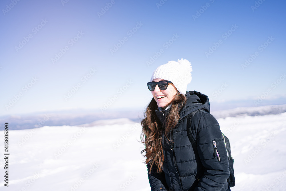 Close up of an attractive woman with sunglasses smiling while walking in the snow on a mountain. Close up of an attractive woman with sunglasses smiling while walking in the snow on a mountain.