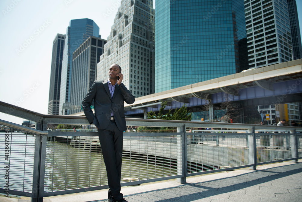 Low angle view of businessman talking on smart phone against buildings Low angle view of businessman talking on smart phone against buildings