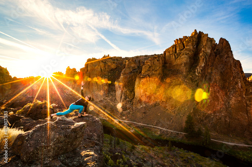 Woman stretching on rock against mountains at Smith Rock State Park on sunny day photo