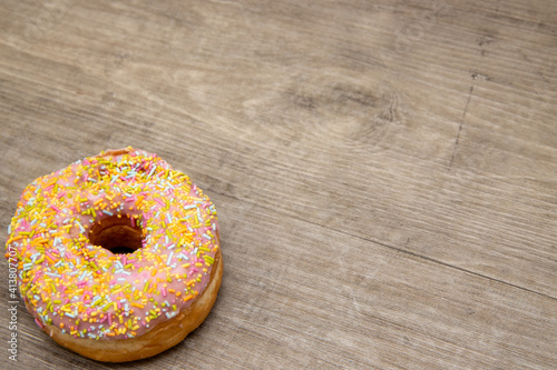 A classic doughnut with sprinkles on a wooden background