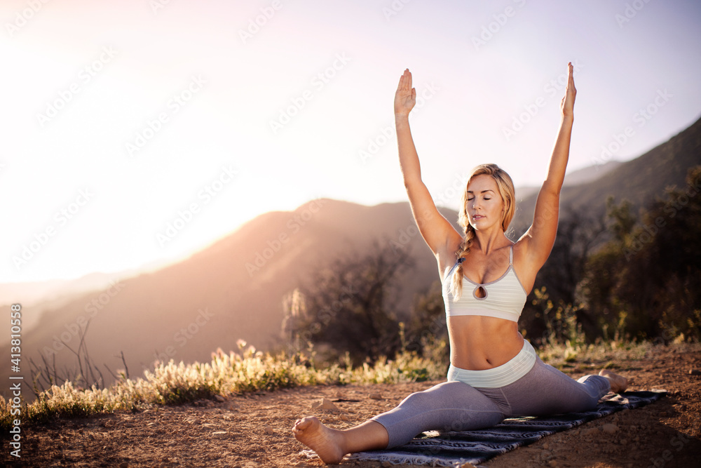 Woman doing splits with arms raised on field against clear sky Woman doing splits with arms raised on field against clear sky